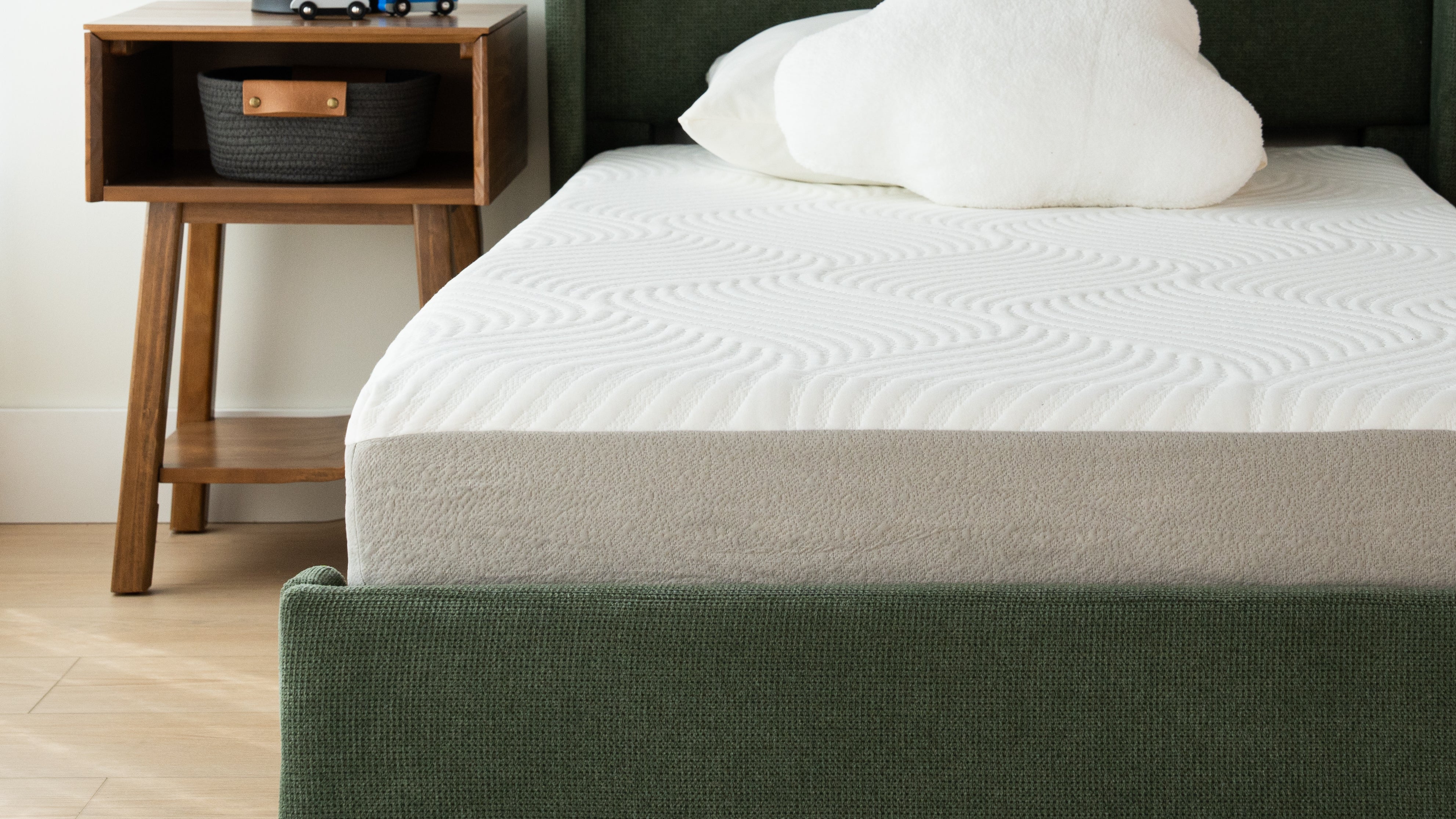 Modern bedroom with a comfortable memory foam mattress on a stylish green bed frame and wooden nightstand.