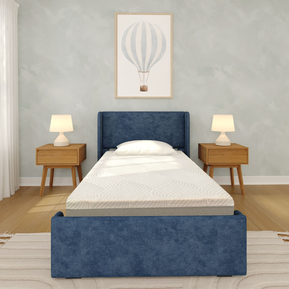 Stylish modern bedroom with a comfortable twin bed featuring a blue upholstered headboard, flanked by wooden nightstands with lamps, and a hot air balloon art print on the wall.