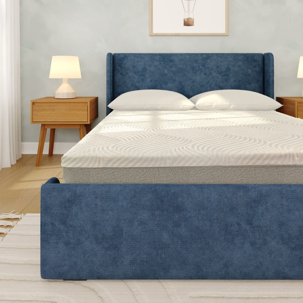Blue upholstered bed with memory foam mattress in modern bedroom setting, featuring wooden nightstands and cozy lighting.