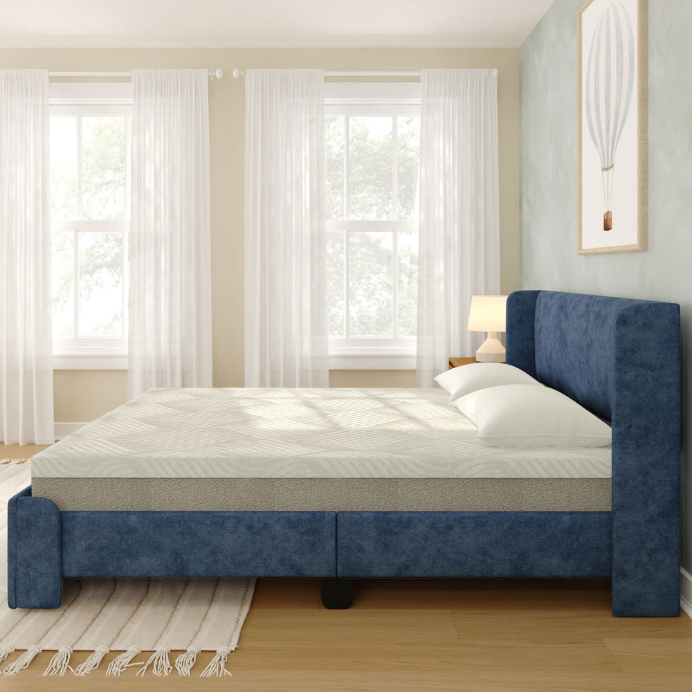 Blue upholstered bed with white mattress in bright, airy bedroom featuring wooden floors and soft natural light.