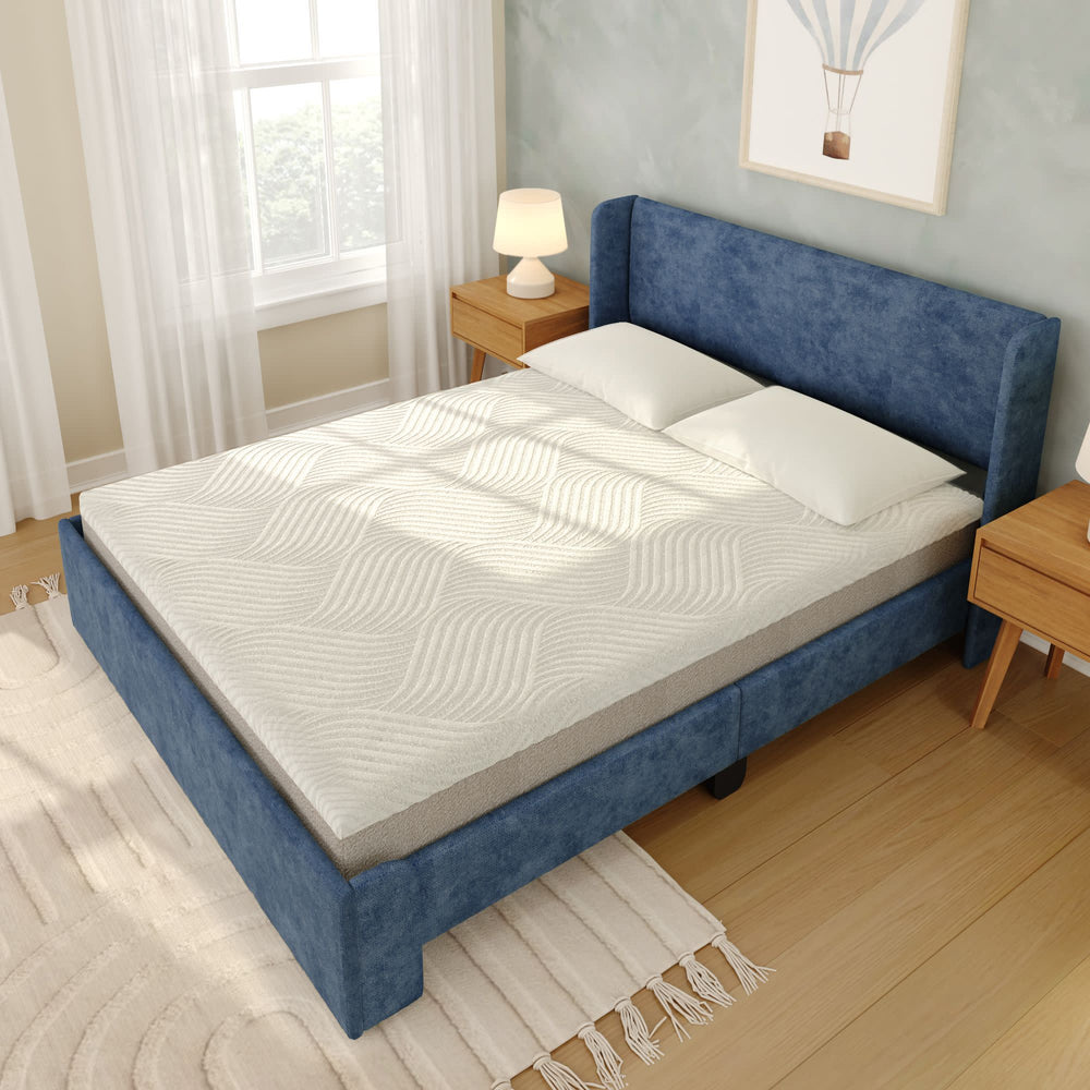 Blue upholstered bed with a comfortable white mattress in a cozy, well-lit bedroom setting.