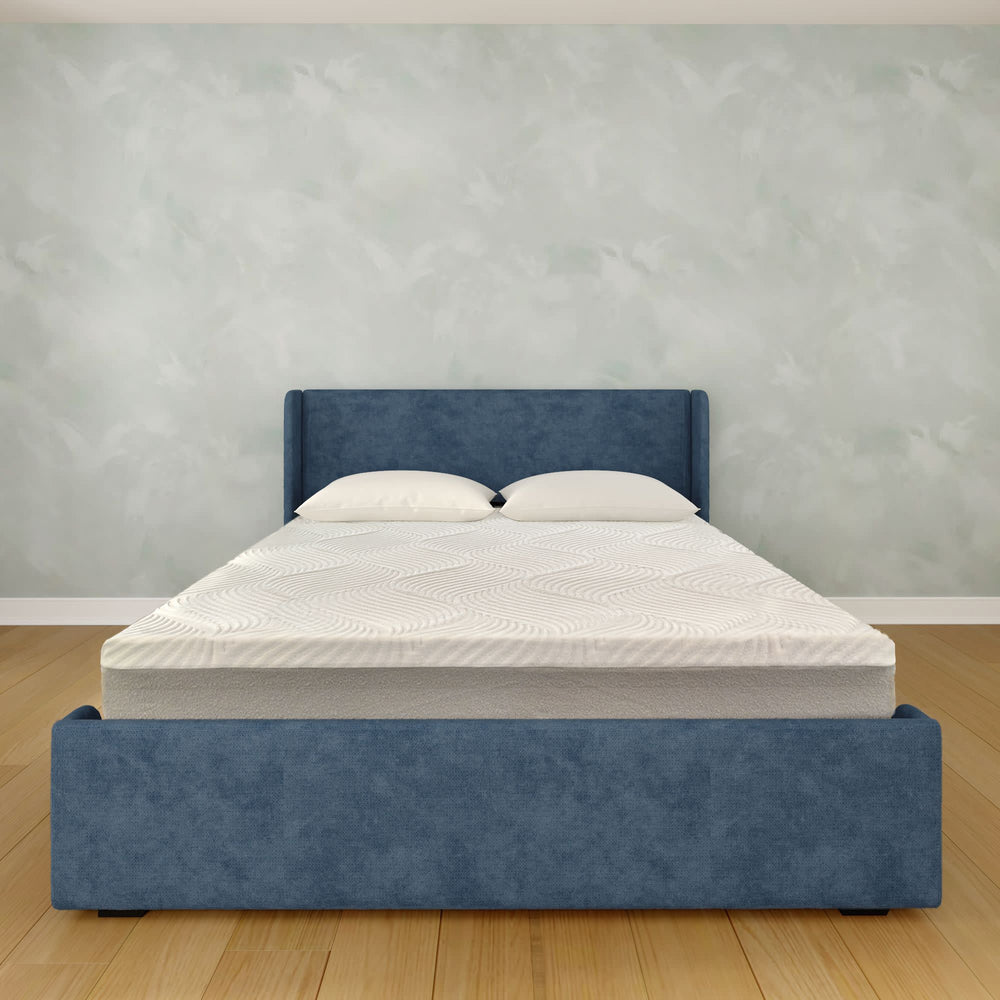 Blue upholstered bed frame with white memory foam mattress in modern bedroom setting.