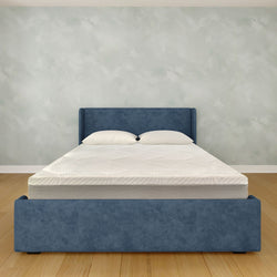 Blue upholstered bed frame with white memory foam mattress in modern bedroom setting.