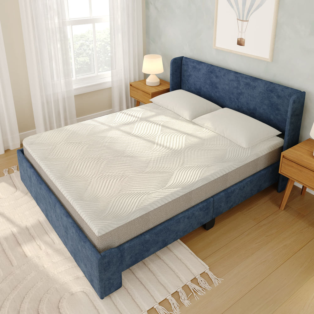 Luxurious bedroom featuring a premium memory foam mattress with a modern blue upholstered frame and cozy pillows, perfect for comfortable sleep.