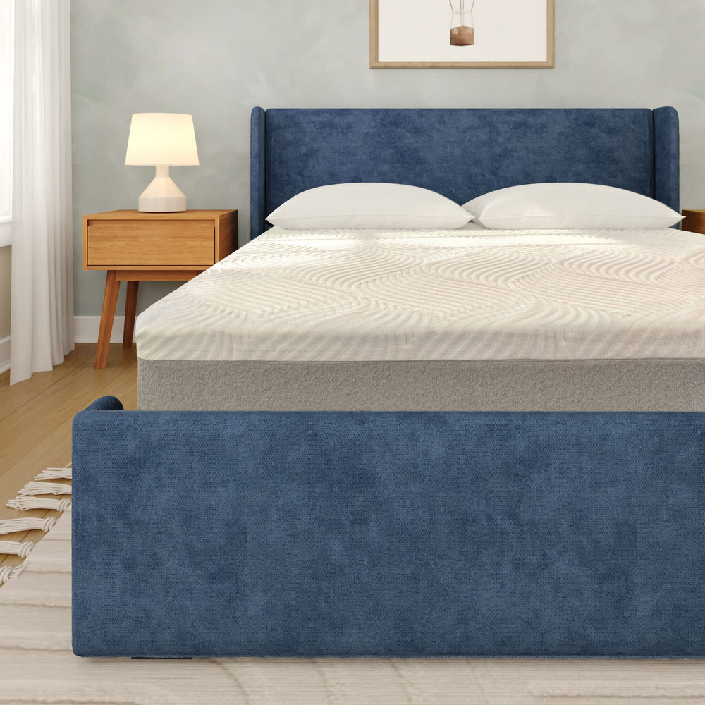 Blue upholstered bed with modern nightstand and lamp in a stylish bedroom setting.