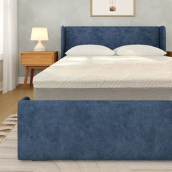 Blue upholstered bed with modern nightstand and lamp in a stylish bedroom setting.