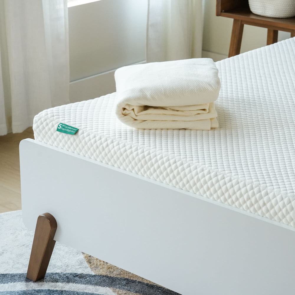 Luxurious white mattress topper with folded cream bedding on modern wooden bed frame.