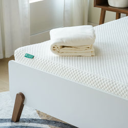 Memory foam mattress with folded cream bedspread on modern bed frame for ultimate comfort and style.