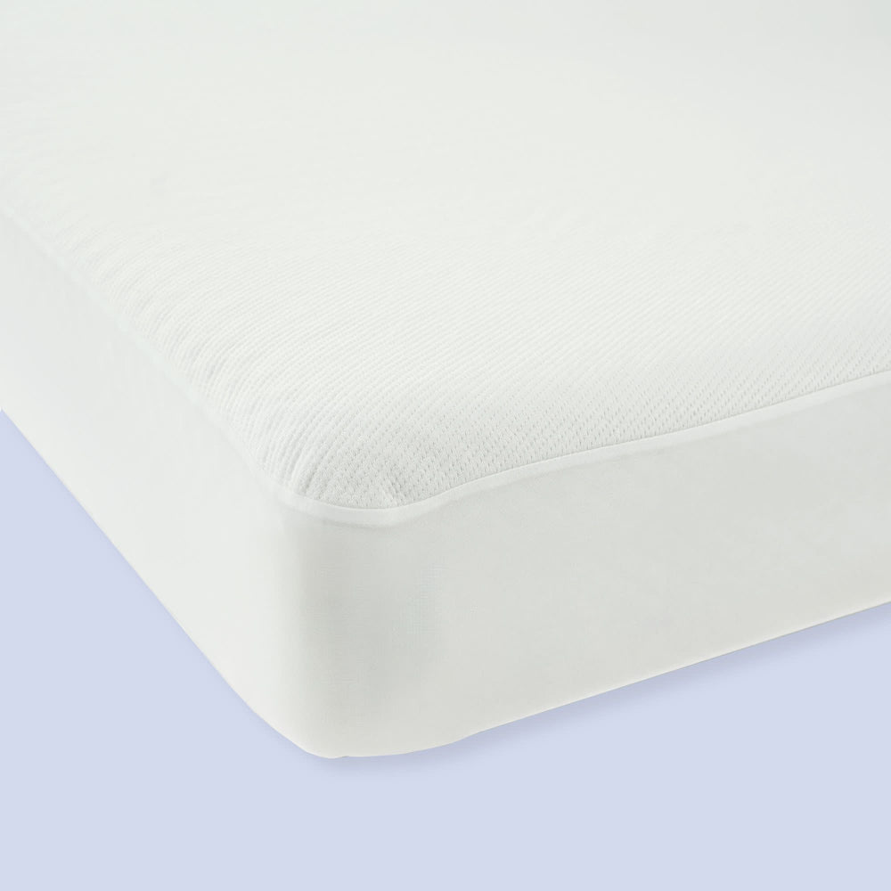 White hypoallergenic mattress protector on bed corner, providing waterproof protection and added comfort.
