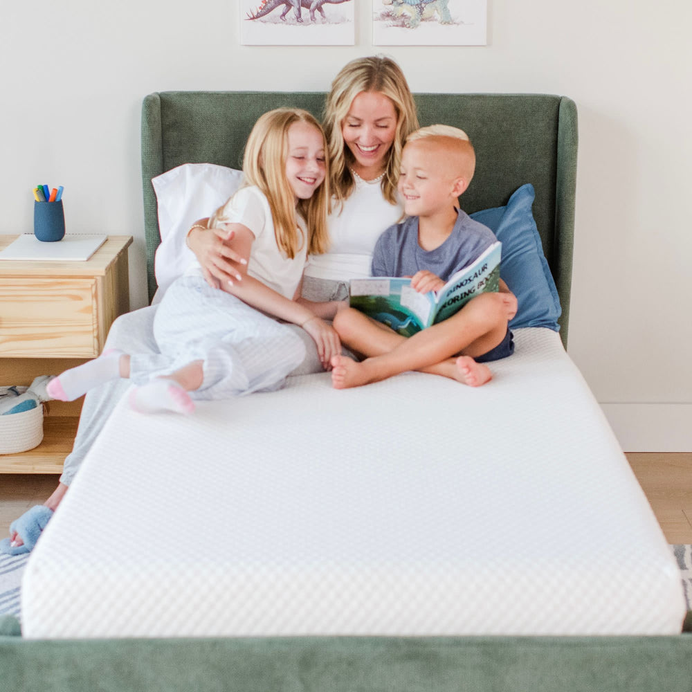 Family enjoying reading time on a comfortable bed with white bedding in a cozy bedroom setting.