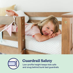 Smiling child lying on a safe bunk bed with wooden guardrails, emphasizing kid-friendly guardrail safety.