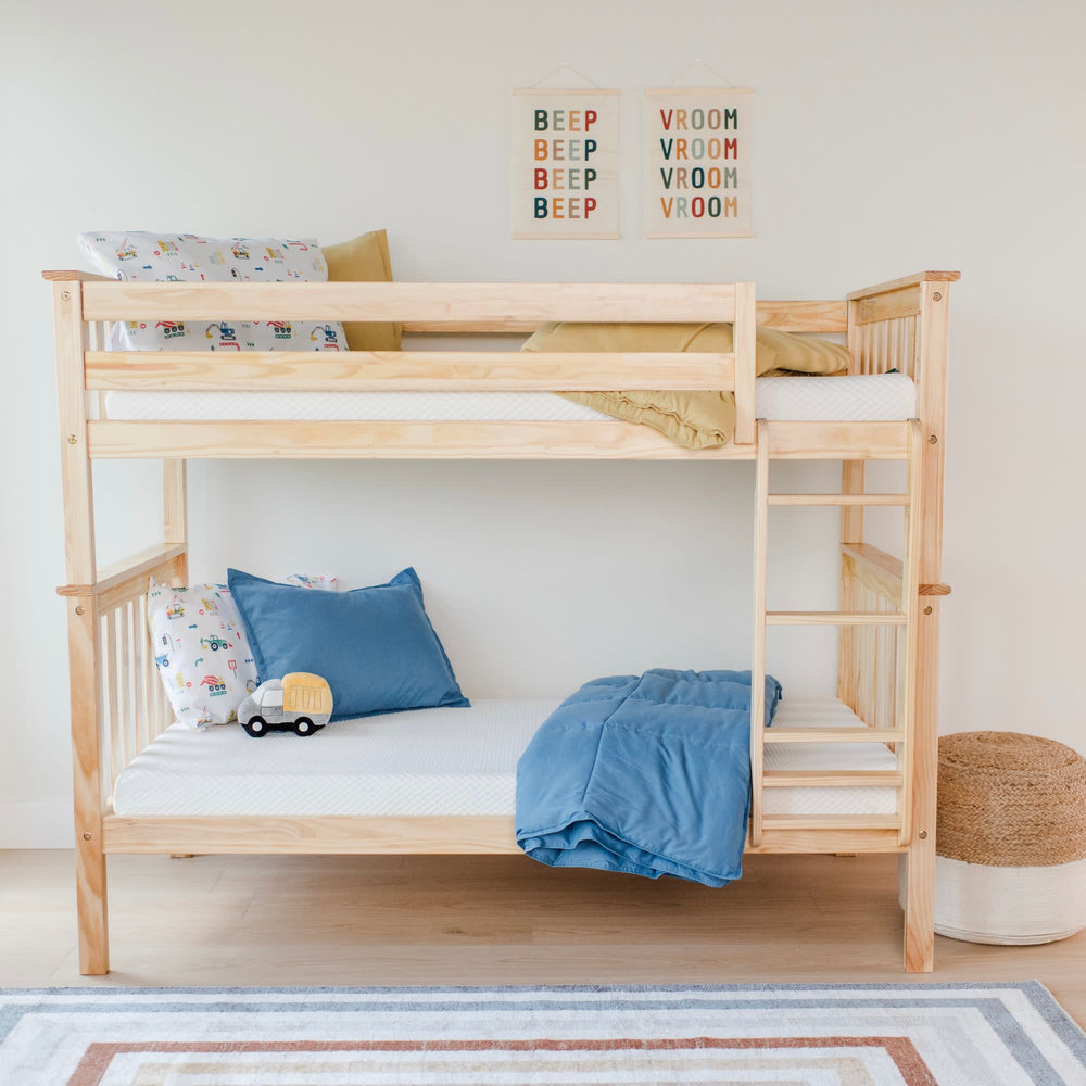 Natural wood children's bunk bed with playful blue bedding and decorative pillows in a bright kids' room.